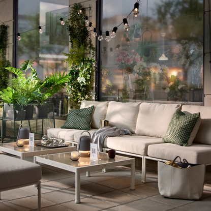 IKEA Plant stand on a patio. There is a large cream garden sofa, coffee table and green cushions.