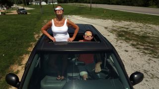 two people watching the solar eclipse from their car. 