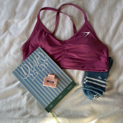 flat lay of gymshark ruched sports bra next to a diary, hair clip and pilates socks