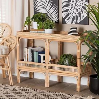 A brown rattan console table from QVC, surrounded by plants