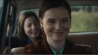 A smiling Dolorus Price (Lola Petticrew) driving her sister Marian (Hazel Doupe) in FX drama series Say Nothing