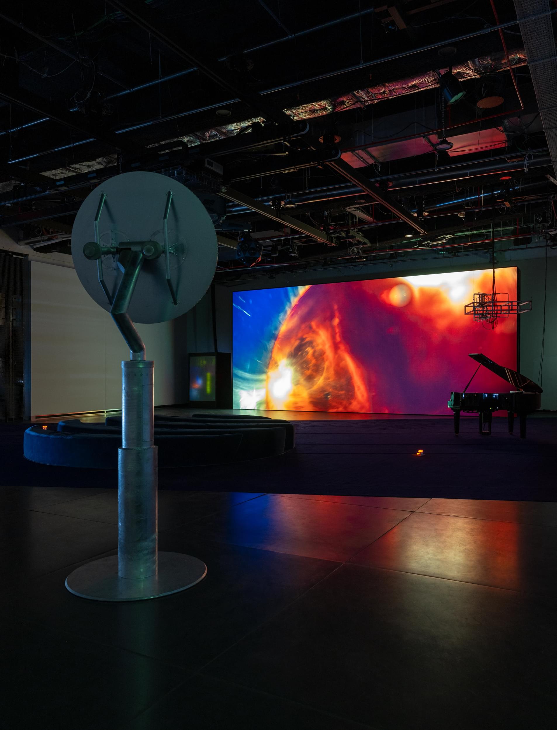 An audiovisual installation features a Mars-looking red shape on a large-scale screen.