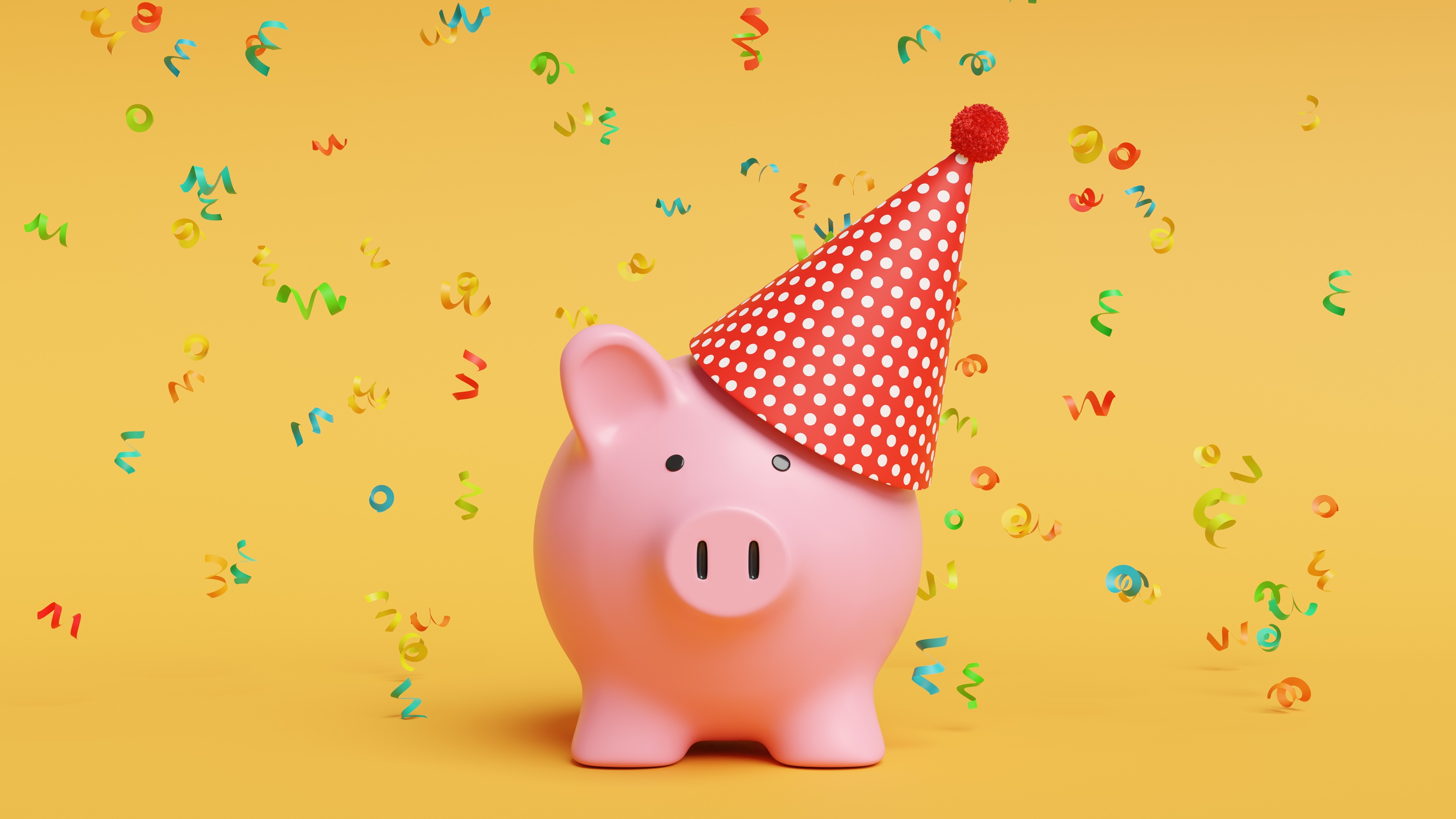 Piggy bank wearing a party hat and surrounded by confetti against a yellow background.