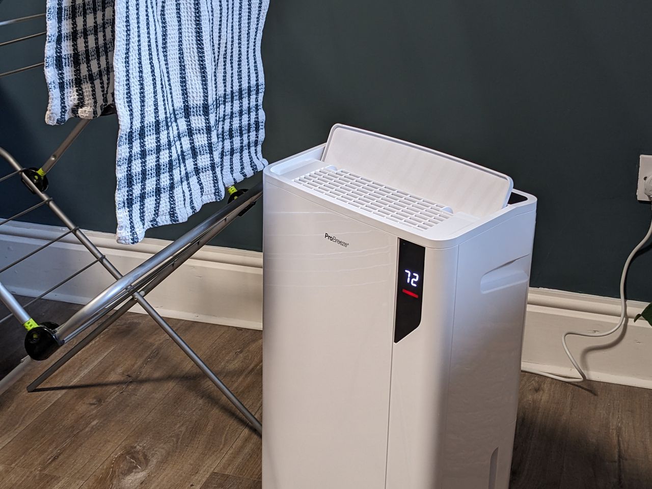 A dehumidifier next to a laundry rack with a tea towel on it