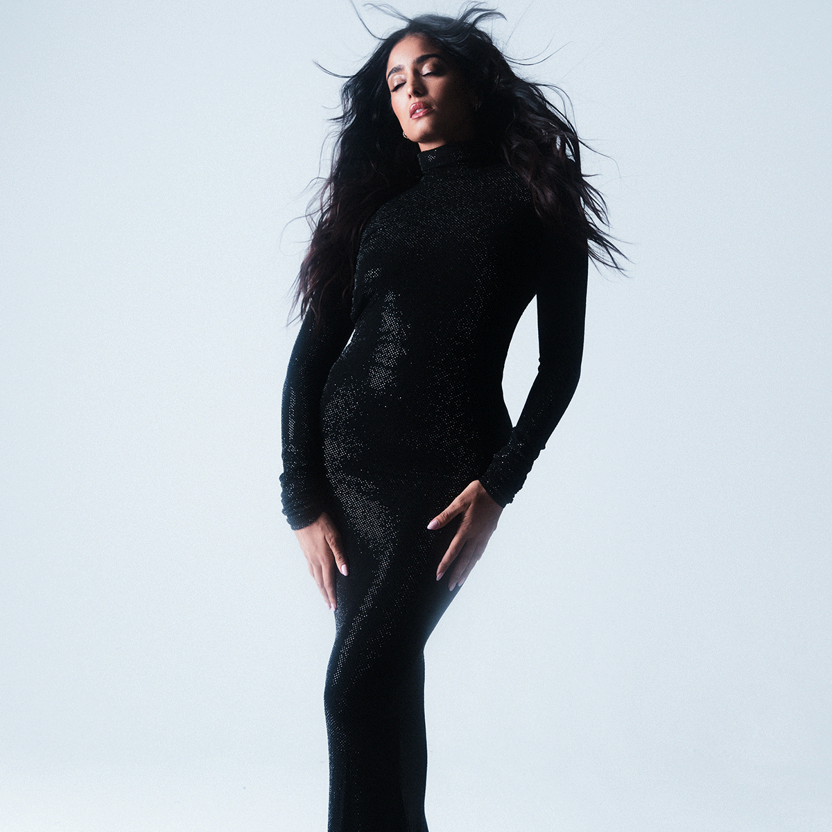 Mandeep Dhillon photographed by Jack Waterlot. She is wearing a black long sleeve bodycon dress. 