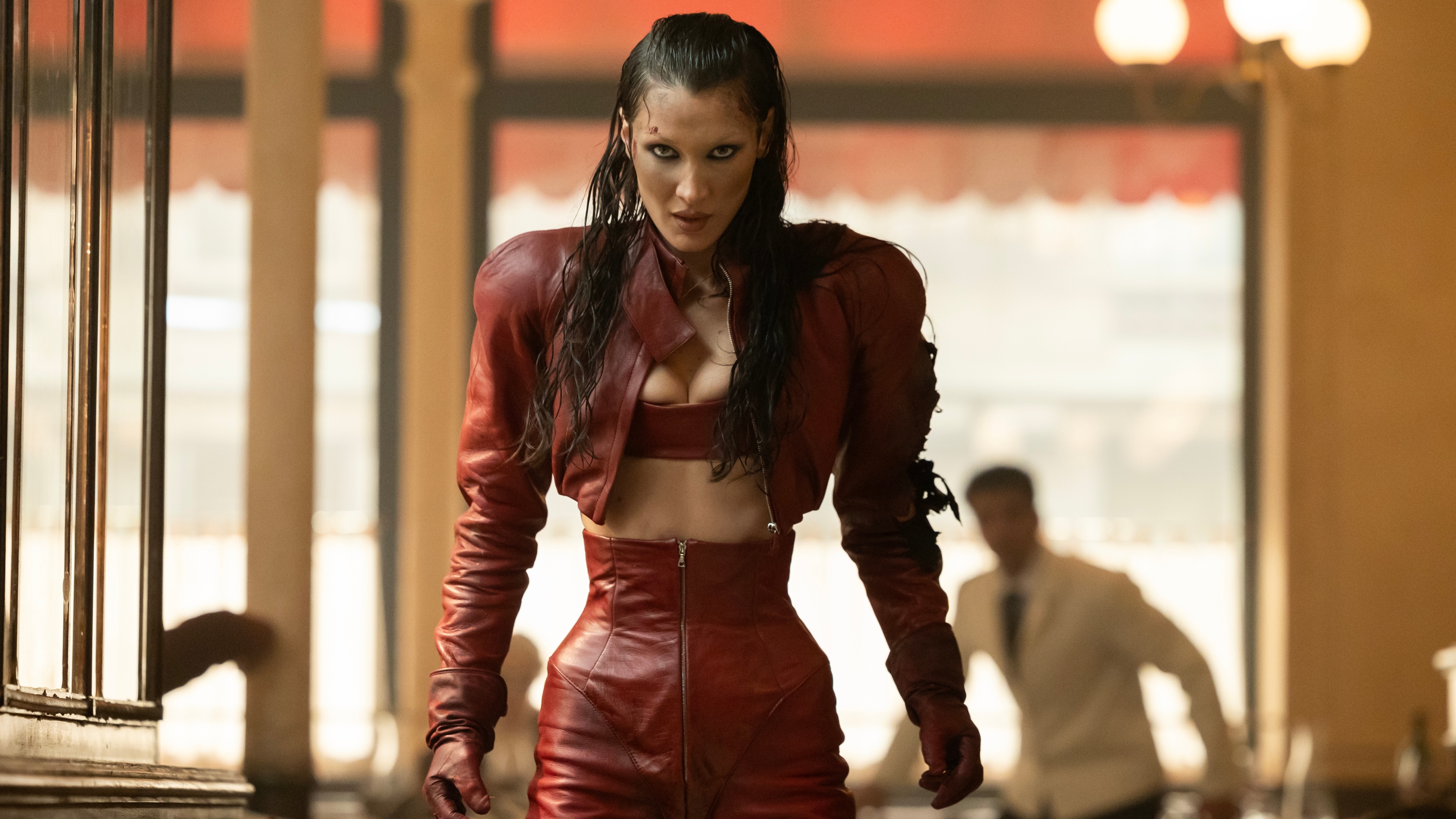 Bella Hadid as Ruby wearing a red latex outfit as she looks angrily at the camera.