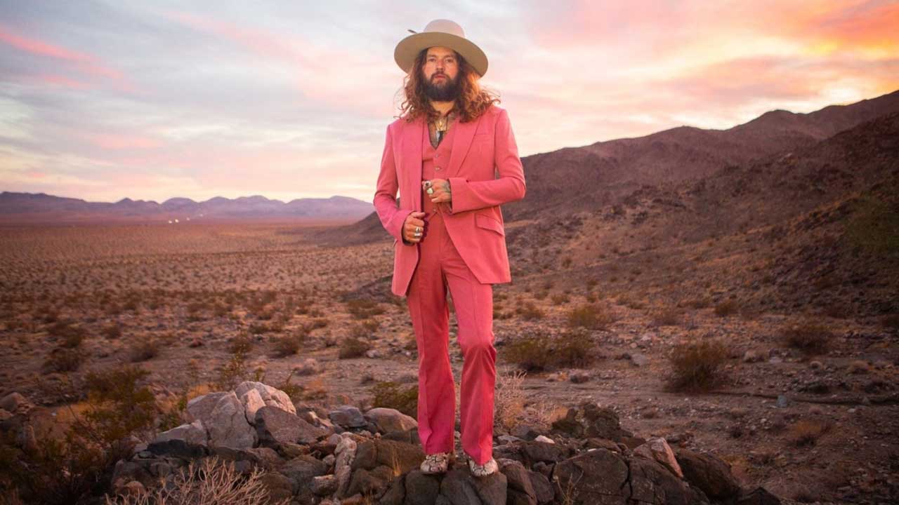 Jay Buchanan in the desert, wearing a pink suit