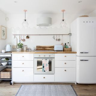 White kitchen with counter, oven, stove, drawers, fridge and grey rug