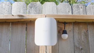 An eero Outdoor 7 mesh extender mounted to a wood fence