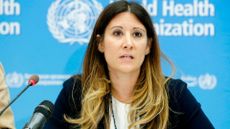 photo of Maria D. Van Kerkhove (a white woman with long brown hair and blonde highlights) sitting in front of a microphone and a large backdrop that reads "world health organization" 