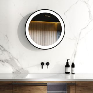 Light up round mirror on wall of bathroom with simple marble wall panel