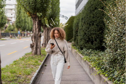 Woman walking down the road with phone, finding out how many calories she burns in a day