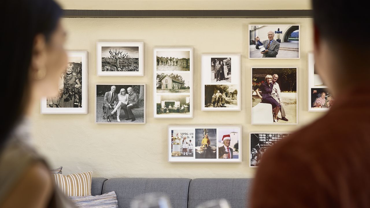 Two visitors looking at Mondavi family photos in the winery reception area