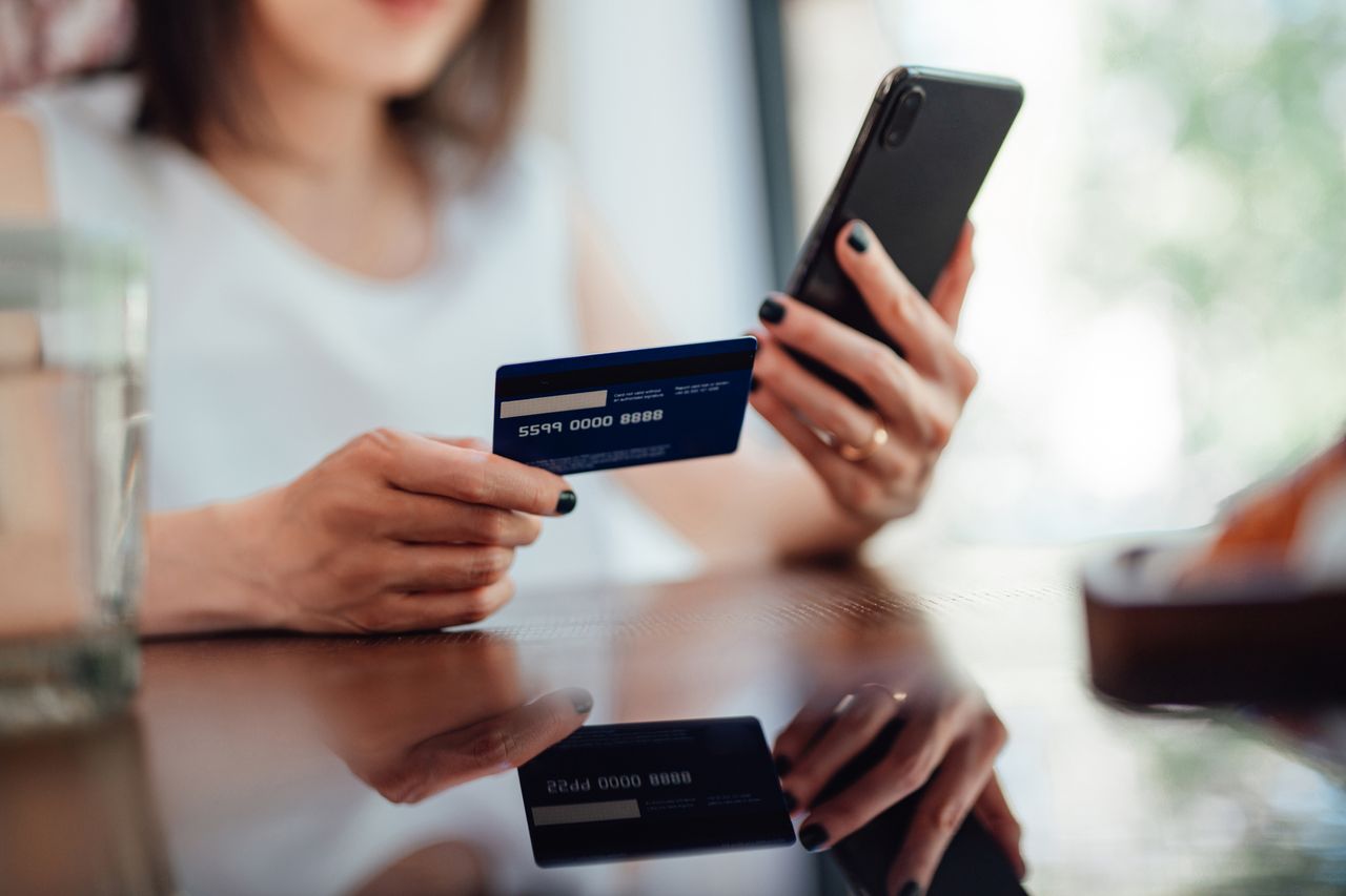 Woman looking at her credit card and phone