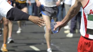 Man accepting water bottle from volunteer at London Marathon