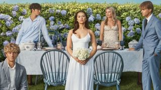 The cast of The Summer I Turned Pretty pose around a wedding dinner table