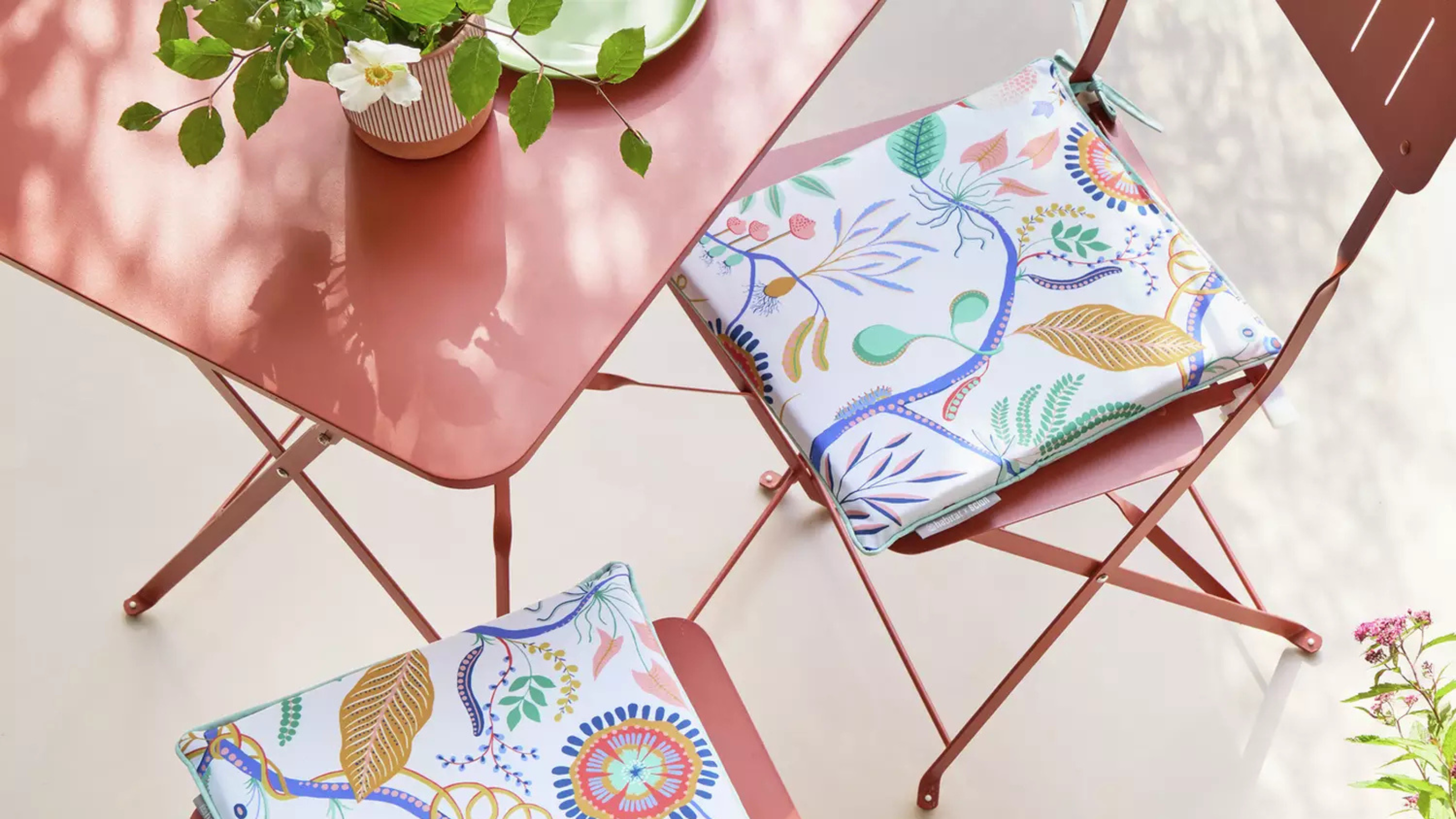 close up of jackfruit print seat cushions on red bistro set.
