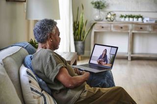 Woman sitting on a couch having a video call on a laptop