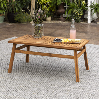 A wooden outdoor coffee table pictured in a garden.
