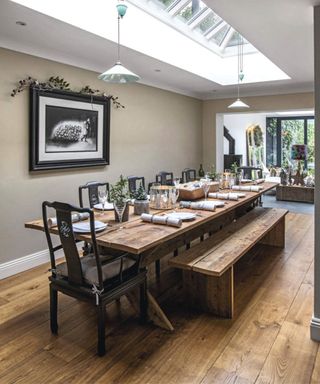Dining room with large wooden table laid for a meal below a large central sky lantern. Light and airy.