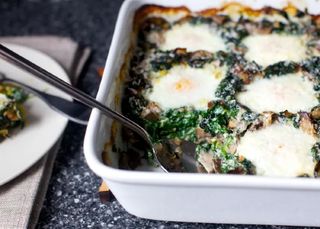 a large white casserole with eggs baked with spinach and mushrooms