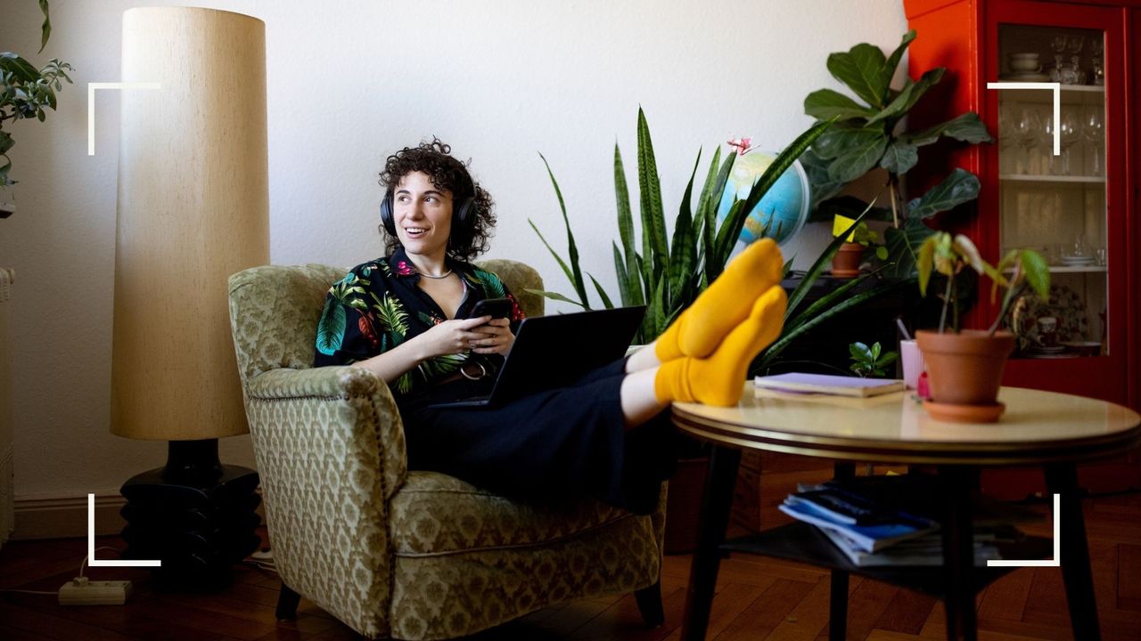 Woman with headphones on, sitting in an armchair relaxing as part of a sunday reset 