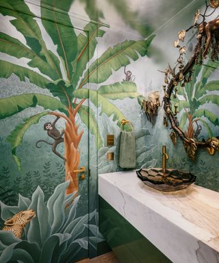 Powder room with a jungle wall mural over a hidden door, interior by Kendall Wilkinson, photograph by Christopher Stark