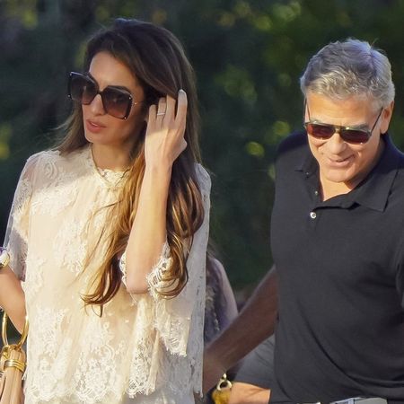 Amal Clooney wearing a lace top with George Clooney