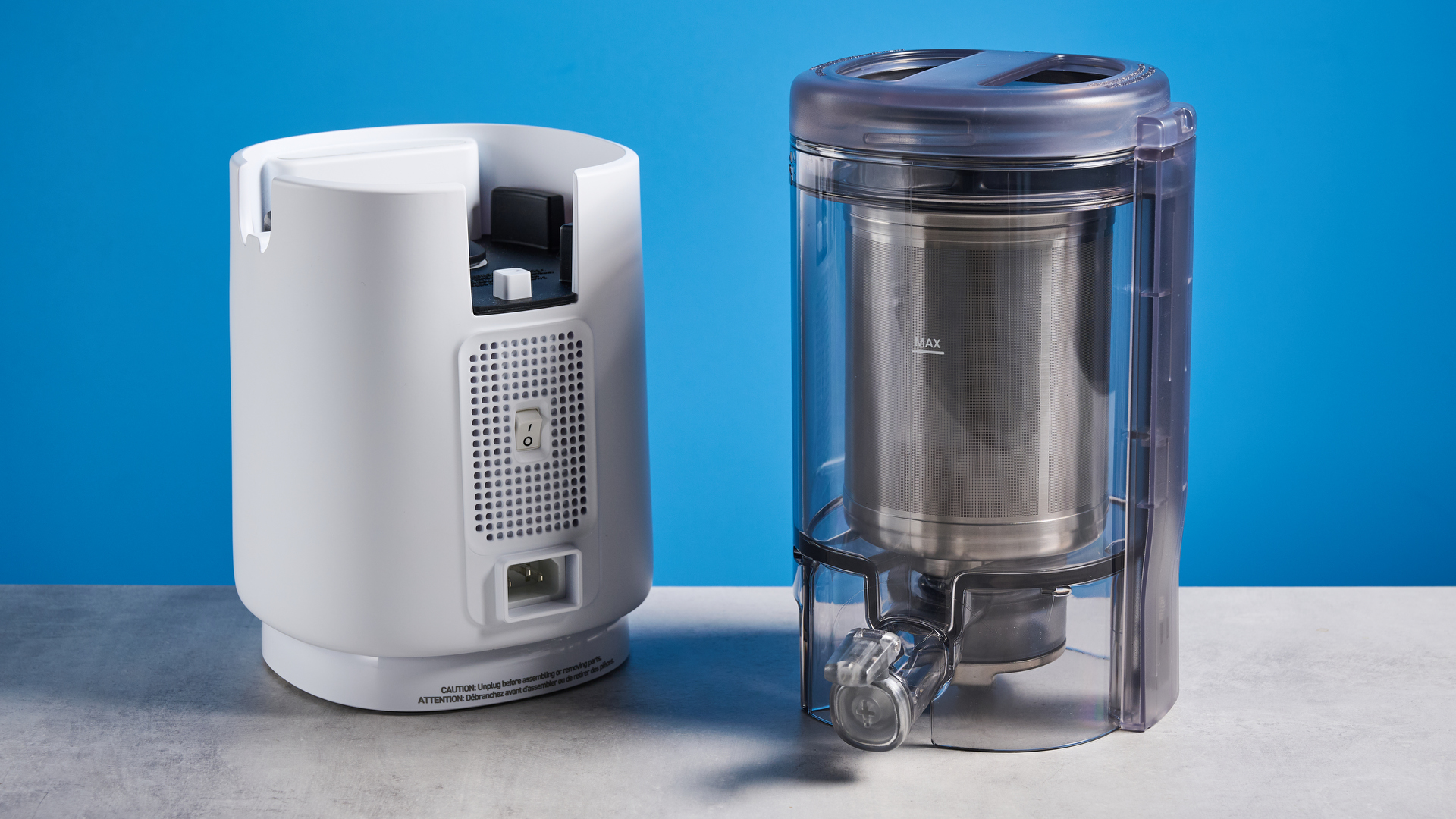 the nama m1 plant-based milk maker in white with a pitcher, blade frame, and strainer, and a pulp mat accessory with a brush
