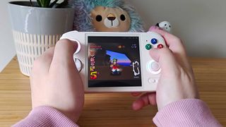 Hands holding Anbernic RG Cube with Crash Team Racing gameplay on screen.