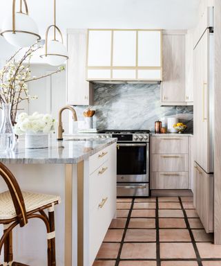 A small kitchen with wood and white cabinets, gold hardware, and a small kitchen island