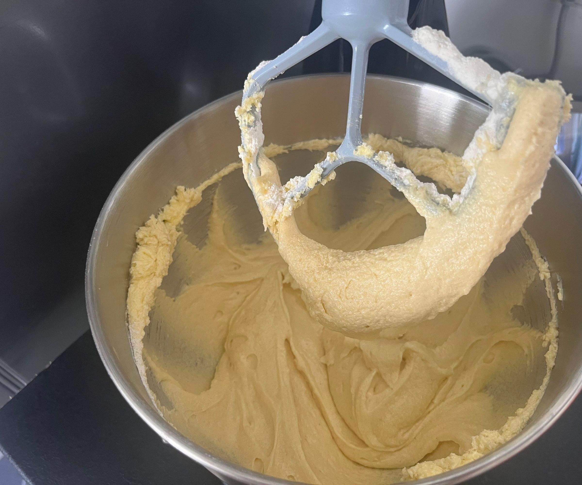 A close up of the raised paddle attachment covered in vanilla cake batter in the SMEG Forte Stand Mixer