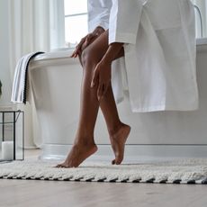 woman applying body lotion to her legs