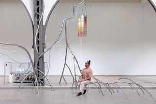performer on tree like installation in exhibition hall
