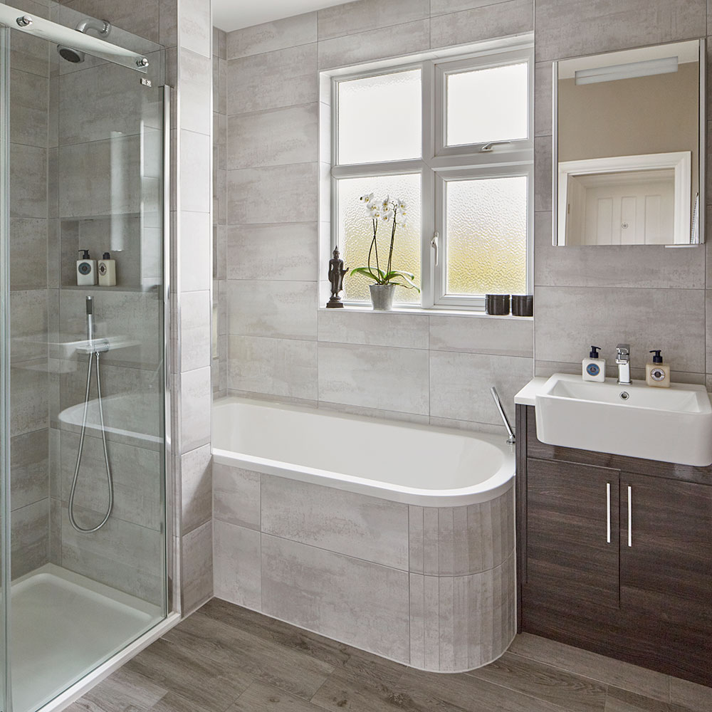 bathroom with grey tiled walls and wooden flooring