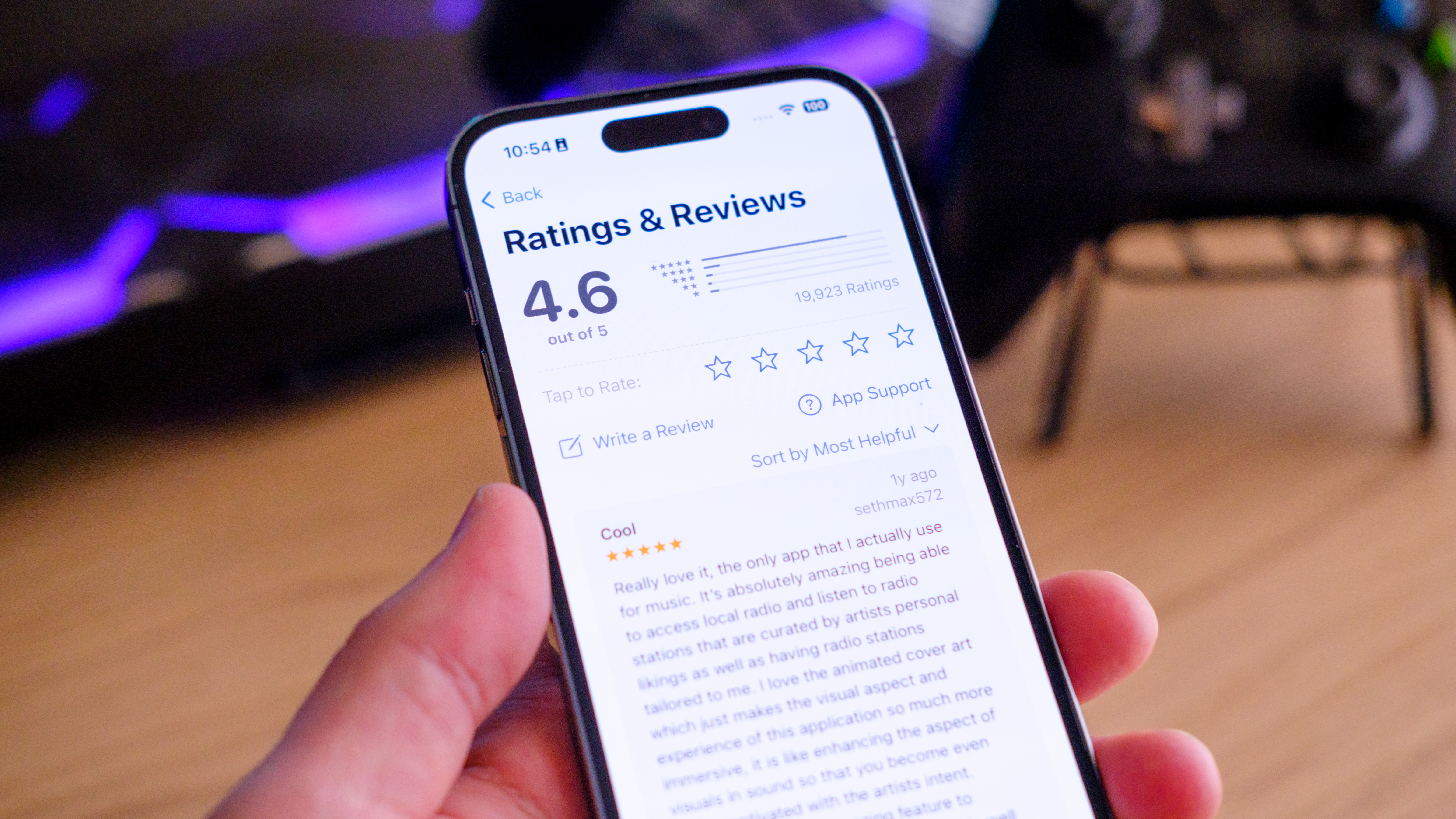 A photo an iPhone in hand, with the Apple Music App Store page open, on the Ratings and Reviews section