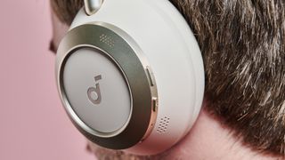 A closeup of a man wearing the Anker Soundcore Space One Pro in front of a pink wall