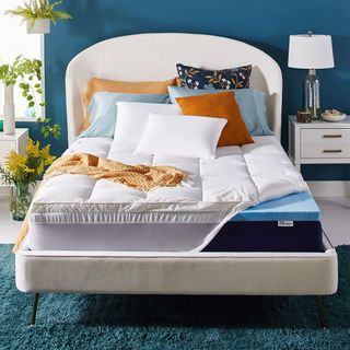 Mattress topper on bed secured with straps and styled with pillows