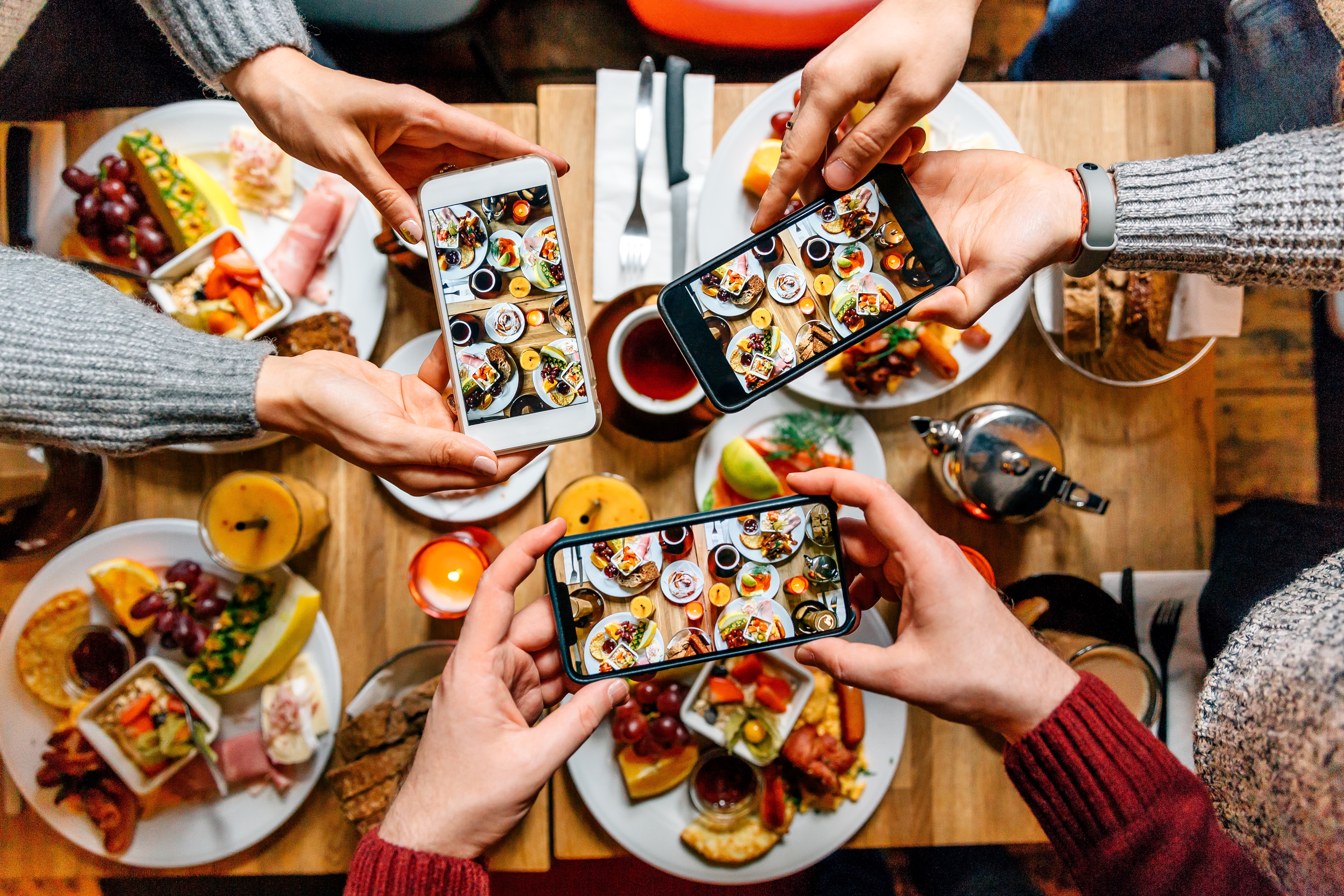 Aerial photo of three people taking photographs of their brunch food