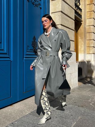 woman wearing knee-high boots with trench coat with clutch
