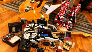 Four electric guitars surrounded by 23 electric guitar humbucker pickups