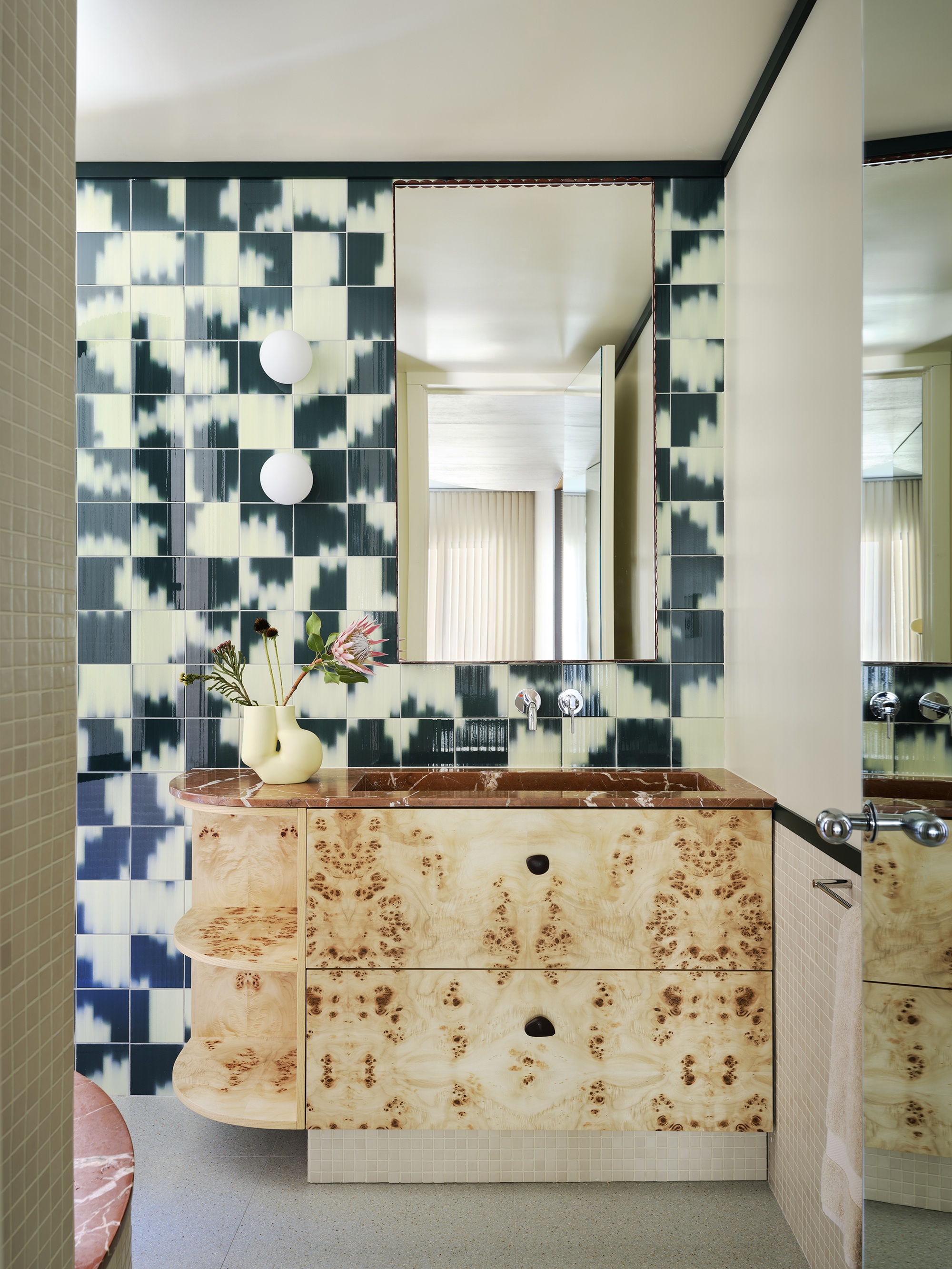 a bathroom with a burl vanity and blurred pattern tiles