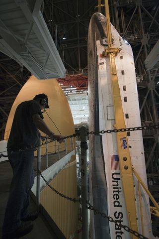 In the Vehicle Assembly Building at NASA's Kennedy Space Center in Florida, a worker monitors the progress of shuttle Atlantis as it is lowered onto the mobile launcher platform where it will be joined with its external fuel tank and solid rocket boosters