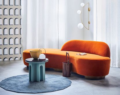 orange curved sofa in a modern living room with round blue coffee table