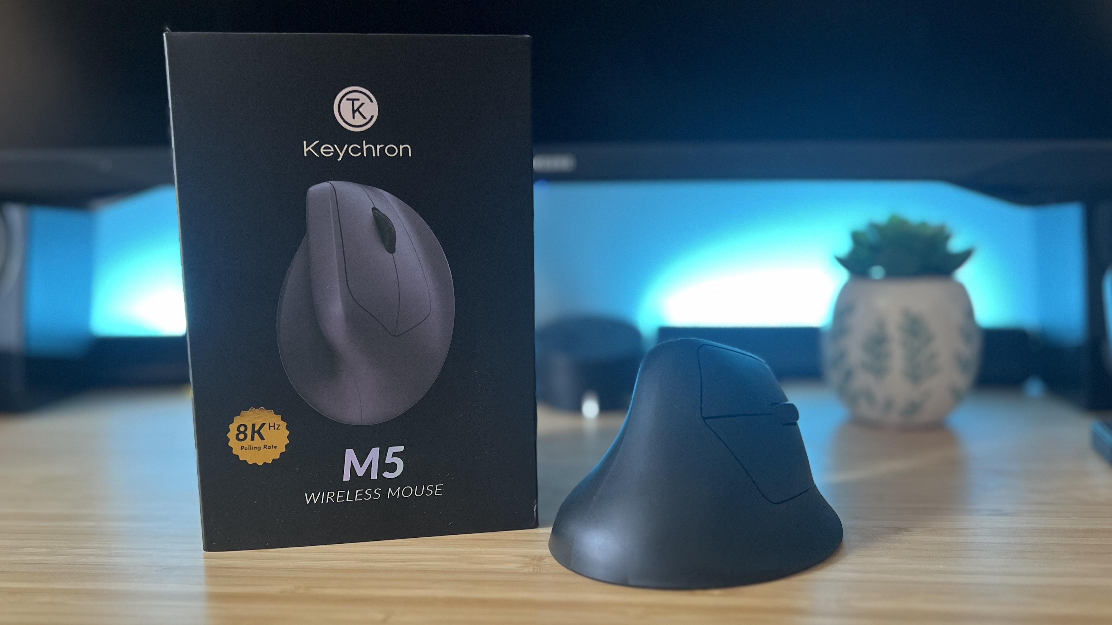 Keychron M5 gaming mouse with packaging on a wooden desk with blue lighting in the background
