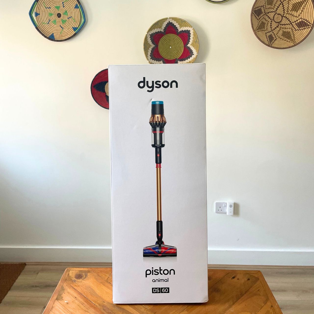 Box of the Dyson V16 Piston Animal sitting on a wooden table in front of a white wall