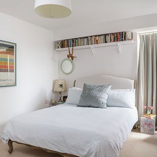 white bedroom with carpet flooring and book shelf