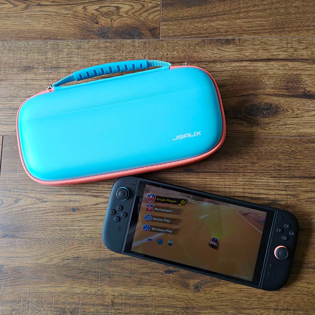 Jsaux Switch 2 carry case in blue next to Switch 2 on woodgrain surface.