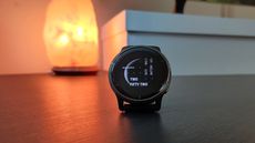 Garmin Venu 2 fitness watch placed on a table in front of a salt lamp