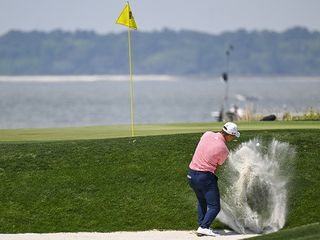 Collin Morikawa hitting a short-sided bunker shot from next to the green